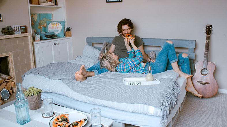 couple is sharing pizza on the bed