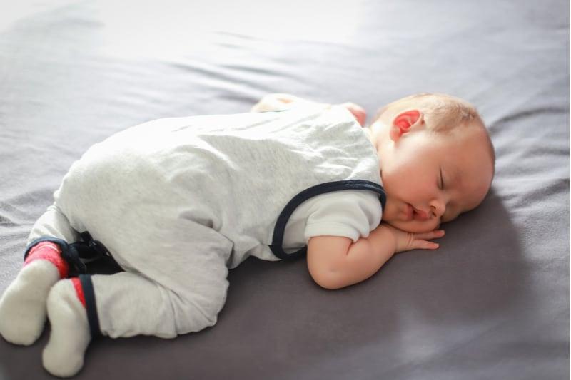 newborn boy sleeps on his stomach on bed