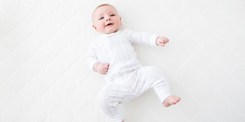 baby laying on back in crib