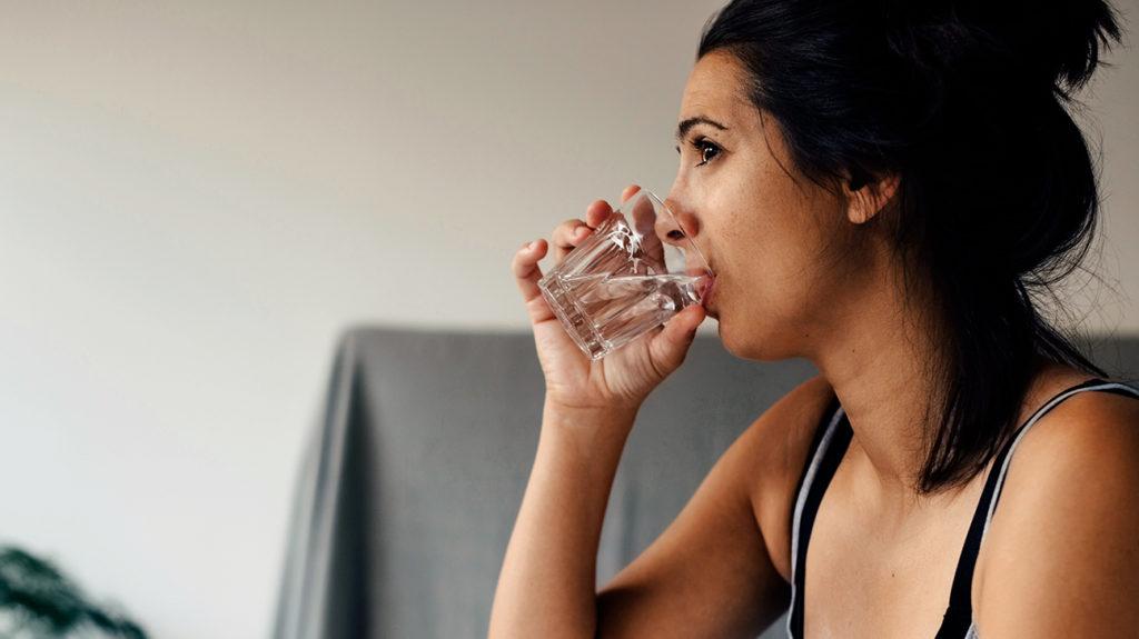 a woman drinking water as that it one way in how to get over jet lag