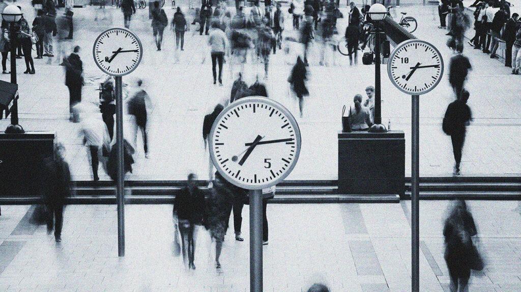 Large clock at train station with people walking around.